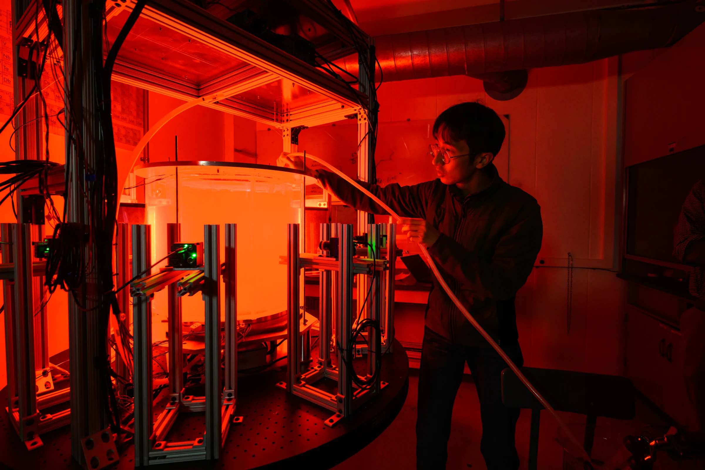 Xinyu Si adjusting tubing on the red-lit ToRoCo rotating-convection apparatus.